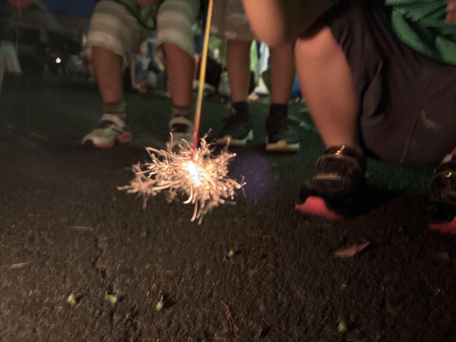 地面近くで火花を散らす手持ち花火と、子どもの足元